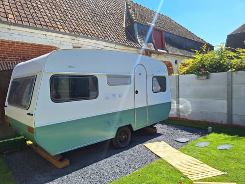Caravane vintage verte et blanche garée dans le jardin de La Cour d'Hortense, chambres d'hôtes à Sailly-Flibeaucourt