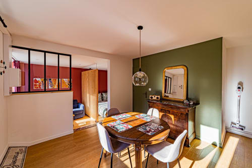 Spacious bedroom with dining area at Gîtes bo in Saint-Romain, featuring green accent wall and wooden furniture