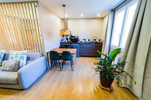 Modern studio at Gites bo in Saint-Romain featuring blue sofa, dining table, wooden floors, and green plant