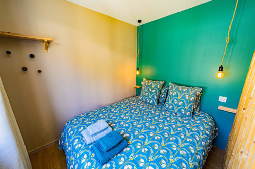 Bright bedroom at Gites bo in Saint-Romain with blue patterned bedding, green accent wall, and pendant lighting