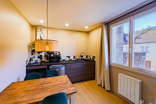 Modern kitchen-dining area at Gites bo in Saint-Romain with wood table, dark cabinetry, pendant light, and countryside views