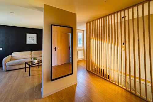Modern hallway at Gites bo B&B in Saint-Romain with wooden slatted divider, mirror, and beige seating area
