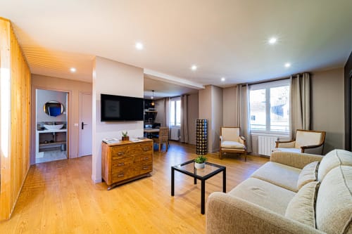 Séjour moderne aux Gîtes bo B&B à Saint-Romain avec parquet, canapé beige et télévision murale
