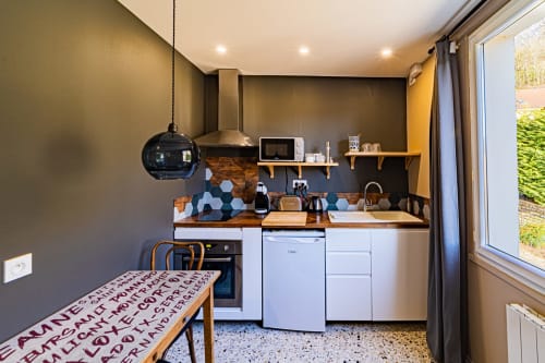 Modern kitchen at Gites bo B&B in Saint-Romain with white cabinetry, hexagonal backsplash, and dining area