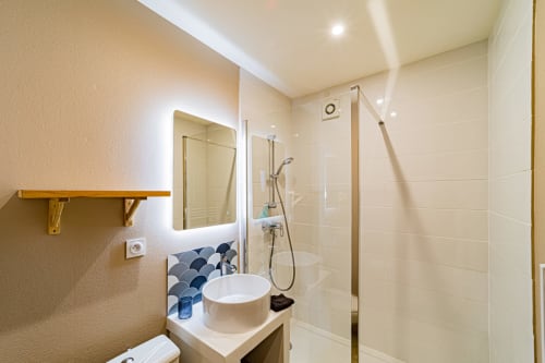 Modern bathroom at Gites bo in Saint-Romain with round vessel sink, illuminated mirror, wooden shelf, and walk-in shower