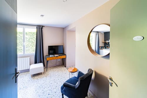 Modern guest room at Gites bo B&B in Saint-Romain with TV, round mirror, armchair, and terrazzo flooring