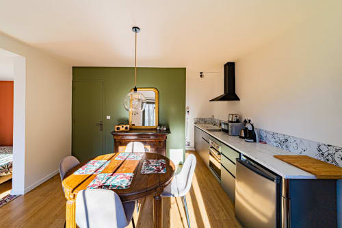 Cuisine-salle à manger moderne de l'appartement Le Boisé aux Gîtes bo, Saint-Romain, avec table en bois, mur d'accent vert et