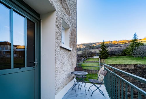 Gites bo balcony in Saint-Romain with table, chairs, railing, and pastoral landscape views