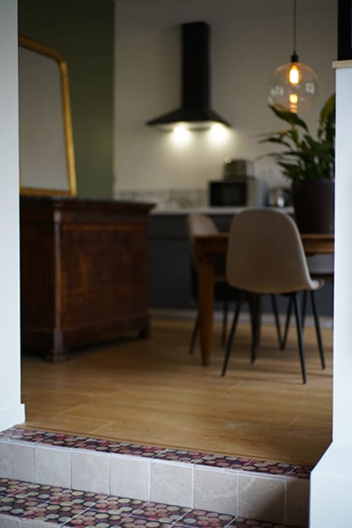 Salle à manger moderne de l'appartement Le Boisé aux Gîtes bo avec luminaires suspendus, table en bois et accès cuisine à Saint-Romain