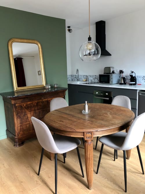 Salle à manger avec table ovale en bois, chaises blanches, miroir et cuisine de l'appartement Le Boisé aux Gîtes bo, Saint-Romain