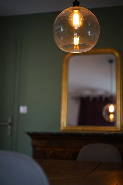 Suspension moderne à abat-jour en verre ambre au-dessus d'un miroir à cadre doré dans l'appartement Le Boisé aux Gîtes bo, Saint-Romain