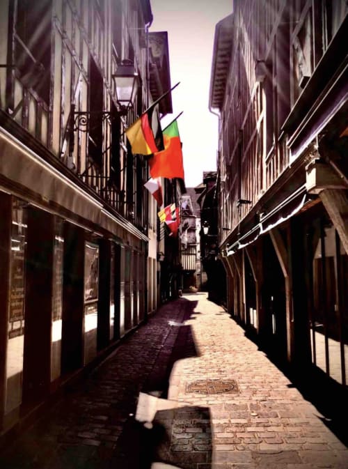 Rue pavée historique de Troyes avec drapeaux français et espagnols accrochés à un lampadaire traditionnel