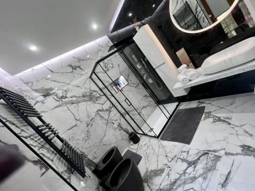 Bagno moderno nell'appartamento Zoelia Roma con pavimento in marmo, vanità nera, specchio, zona doccia e asciugamani bianchi