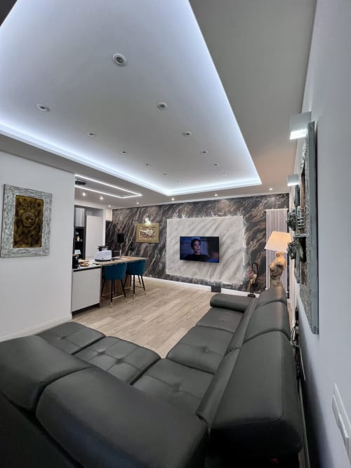 Moderno appartamento Zoelia a Roma con divano grigio, parete in marmo, TV, zona lavoro e illuminazione LED al soffitto