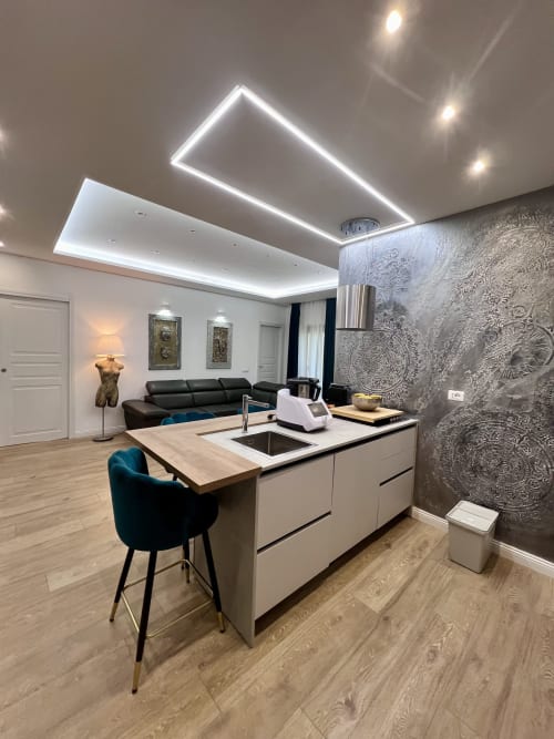 Cucina open-plan moderna con zona living nell'appartamento Zoelia Roma, illuminazione al neon al soffitto e rivestimenti decorativi testurizzati