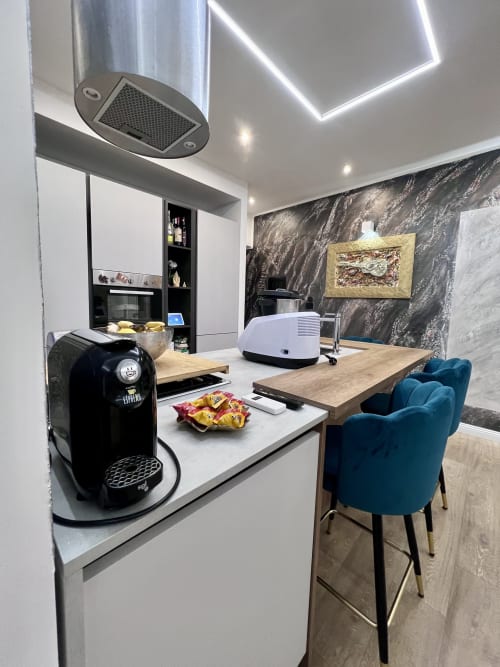 Cucina moderna nell'appartamento Zoelia Roma con macchina Nespresso, rivestimento in marmo, banconi in legno e sedute in velluto blu