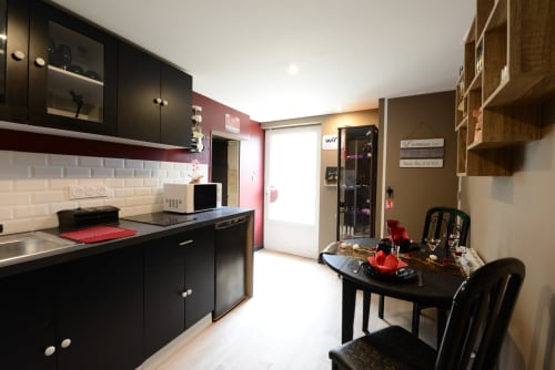 Cuisine moderne noire avec accents rouges, table à manger et étagères intégrées aux Secrets de Winna