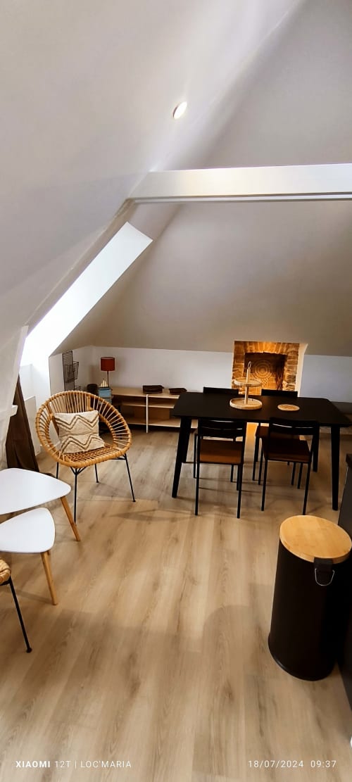 Appartement moderne en mansarde avec table à manger, fauteuil en rotin, parquet et cheminée à Loc'Maria, Belle Île en Mer