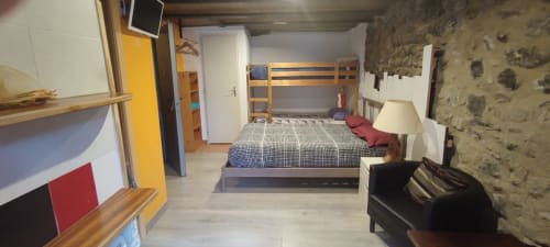 Amplia habitación compartida en La Calma De Bellver con literas, zona de estar confortable y muros de piedra rústica en Bellver de la