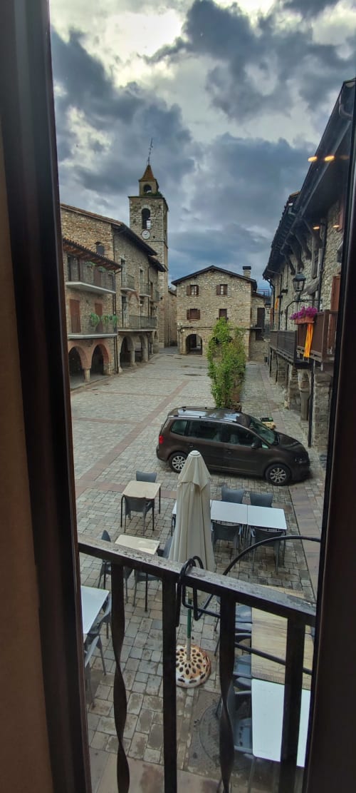 Plaza medieval de Bellver de la Cerdanya vista desde el balcón de La Calma, edificios de piedra y torre de iglesia