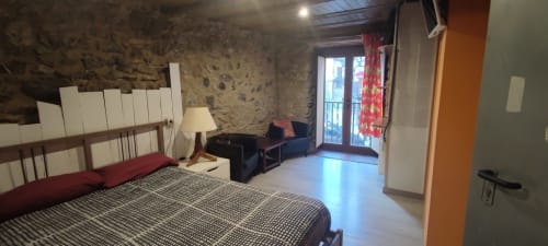 Habitación espaciosa en hostal La Calma De Bellver con cama, acceso a balcón, paredes de piedra y comodidades modernas en Bellver de la
