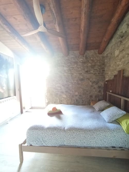 Habitación luminosa en el hostal La Calma De Bellver con cama, vigas de madera vista, muros de piedra y vistas a la montaña