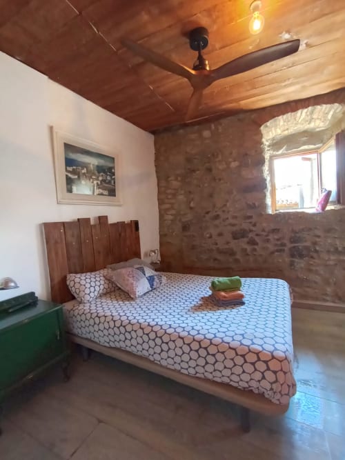 Acogedora habitación en el albergue La Calma De Bellver en Bellver de la Cerdanya con ventilador de madera, pared de piedra y diseños