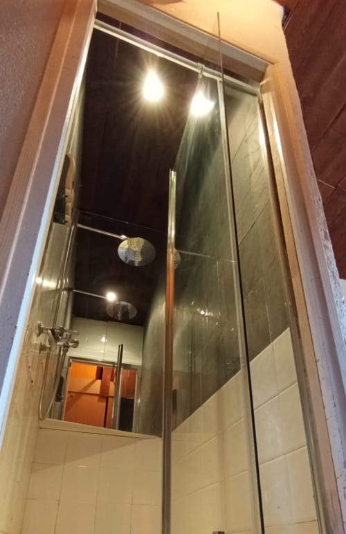 Baño moderno con ducha de cristal e iluminación cenital en el albergue La Calma De Bellver en Bellver de la Cerdanya,