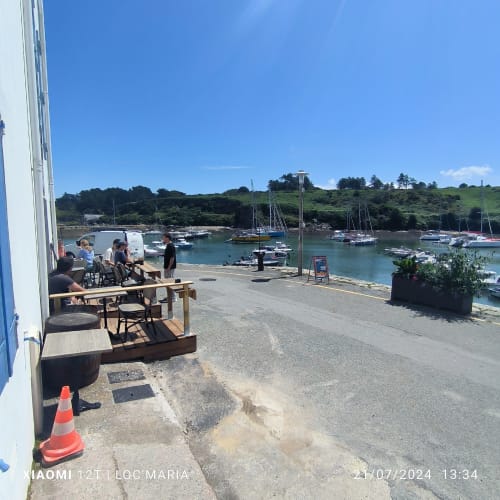 Terrasse en bord de mer à Loc'Maria Belle Île avec voiliers au mouillage et collines verdoyantes