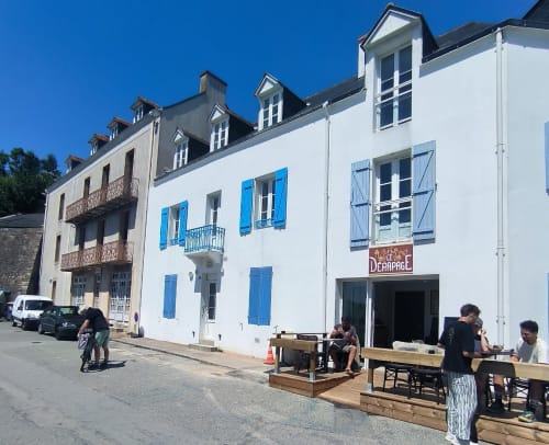 Charmant bâtiment blanc aux volets bleus et terrasse de café à Locations Loc'Maria, Belle Île en Mer, France