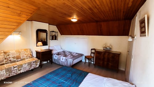 Chambre mansardée du gîte Loc'Maria à Belle Île avec plafond en bois, lit, canapé et mobilier traditionnel