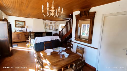 Intérieur spacieux du cottage avec plafond en bois, table à manger, cheminée et escalier à Loc'Maria Belle Île-en-Mer
