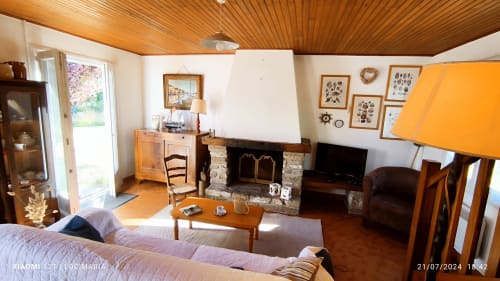 Séjour de cottage avec cheminée, plafond aux poutres apparentes, vue jardin, TV et coin détente à Locmaria Belle Île en Mer