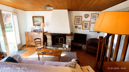 Spacieux séjour avec cheminée, plafond à poutres apparentes, TV, coin salon et vue sur jardin à Loc'Maria Belle Île