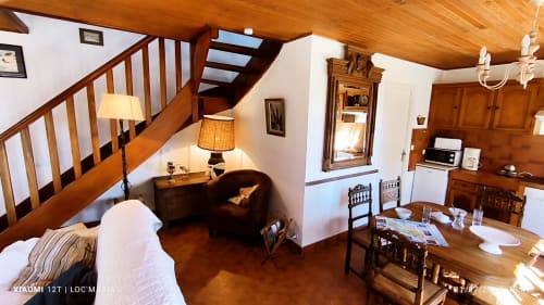 Intérieur du cottage Maison Martha avec poutres apparentes, escalier, salon, table à manger et cheminée à Loc'Maria, Belle-Île