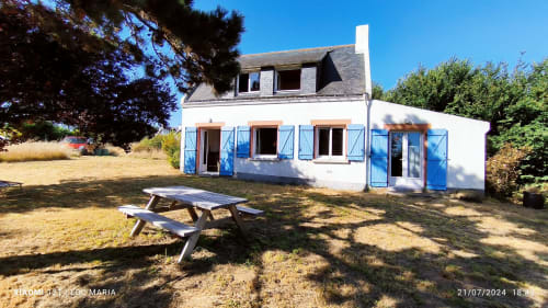 Chaumière blanche aux volets bleus et table de pique-nique dans le jardin de Loc'Maria, Belle Île-en-Mer, France