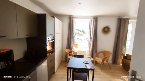 Studio à Loc'Maria Belle Île avec vue mer, table à manger, chaises en rotin et cuisine moderne