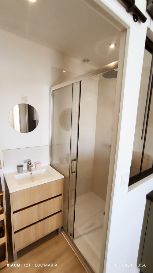 Salle de bain moderne du Studio La Reine de Guerveur, Loc'Maria Belle Île en Mer, avec vasque, miroir rond et douche vitrée