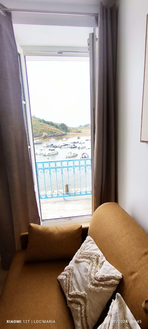 Studio vue mer avec fauteuil moutarde surplombant le port de Locmaria et les bateaux, Belle-Île-en-Mer