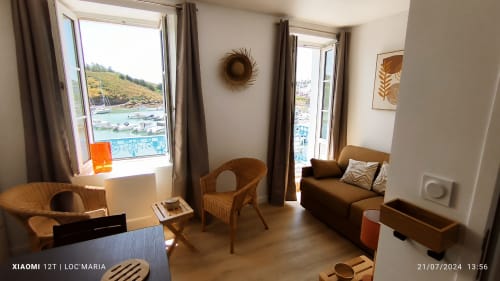Lumineux appartement côtier avec fauteuils en rotin, canapé marron et vue sur mer à Loc'Maria, Belle-Île-en-Mer