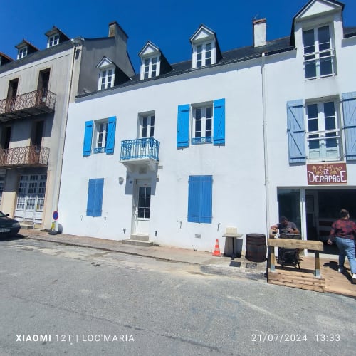Bâtiment blanc aux volets et portes bleus, appartements Loc'Maria à Locmaria, Belle Île en Mer, France