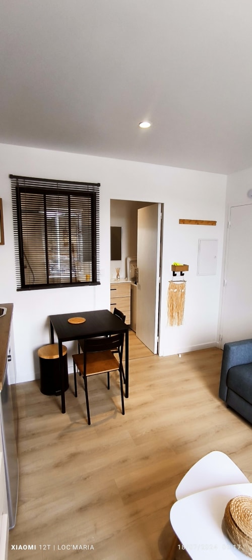 Studio moderne avec table à manger noire, parquets en bois et accès à la salle de bains à Loc'Maria, Belle-Île-en-Mer