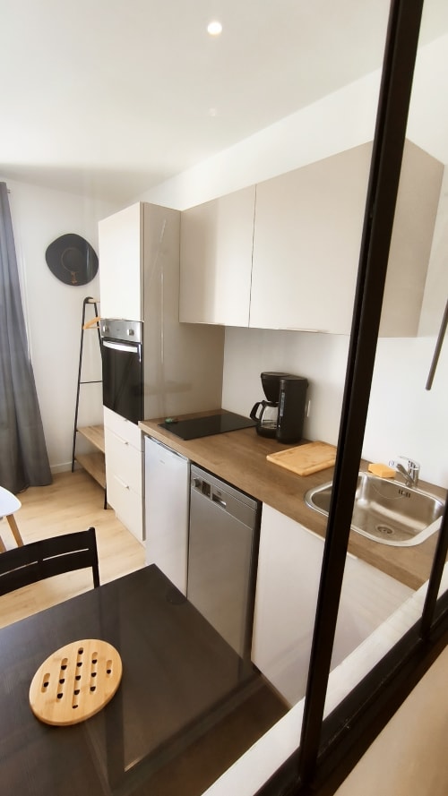 Cuisine moderne avec meubles blancs, plans de travail en bois et espace repas à Locmaria, Belle Île-en-Mer