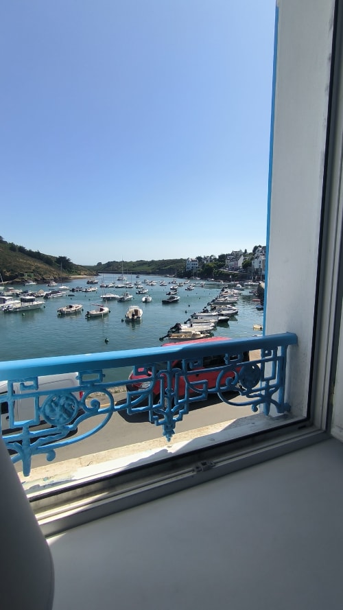 Balustrade bleue de balcon dominant le port turquoise avec bateaux amarrés à Locmaria, Belle-Île-en-Mer