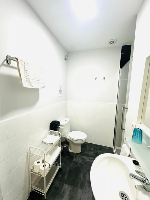 Baño moderno y limpio en el apartamento Gestyp-AT de Mérida con azulejos blancos, piso negro, inodoro, bañera y ducha
