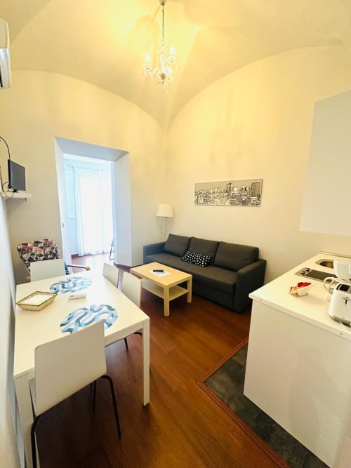 Apartamento moderno en Mérida con sala abierta de paredes amarillas, sofá negro, escritorio de madera y cocina