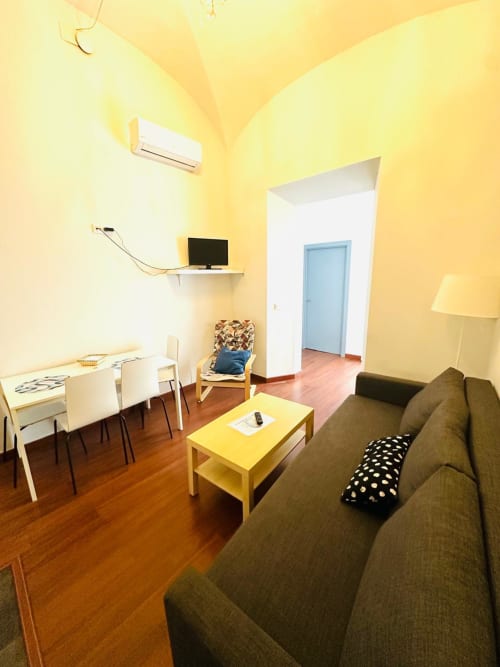 Luminoso salón de apartamento en amarillo brillante con sofá, comedor y puerta azul en Mérida