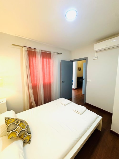 Dormitorio moderno en apartamento Gestyp-AT en Mérida con cama queen, cortinas rojas y acceso a vista al jardín