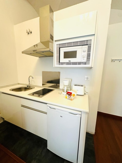 Pequeña cocina en apartamento de Mérida con electrodomésticos blancos, microondas y estufa
