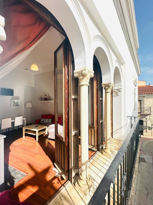 Terraza de apartamento moderno en Mérida con columnas coloniales, puertas de madera y vistas a hitos arquitectónicos